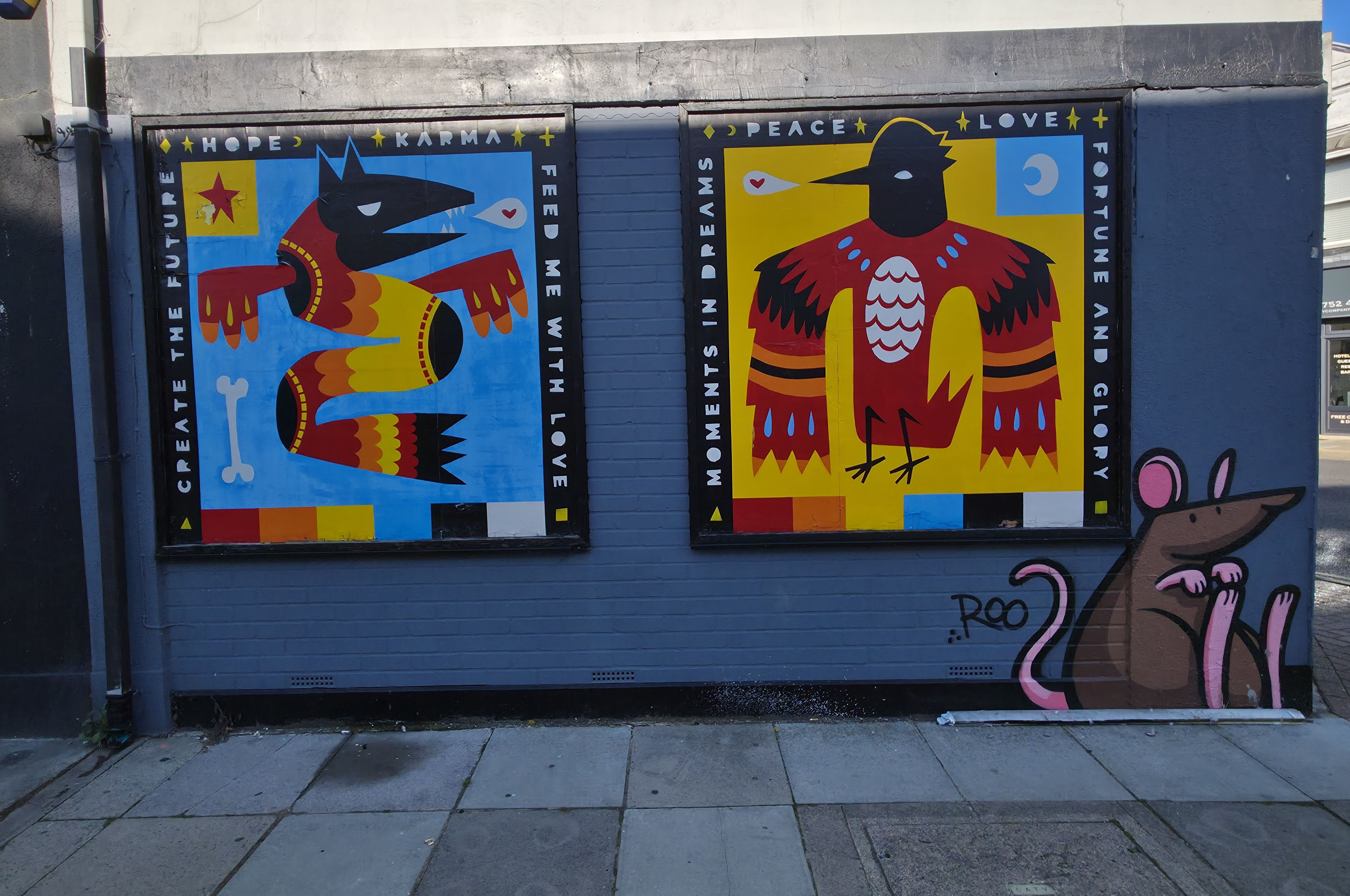 Photo of two brightly dressed Egyptian looking creatures, with words like love and peace, karma, love, hope, feed me with love fortune and glory, and moments in dreams written on their frames, found in Albert Road, Southsea, Hampshire, United Kingdom. Photo taken by Baldi, A.K.A Amonn AL-Mahrouq.