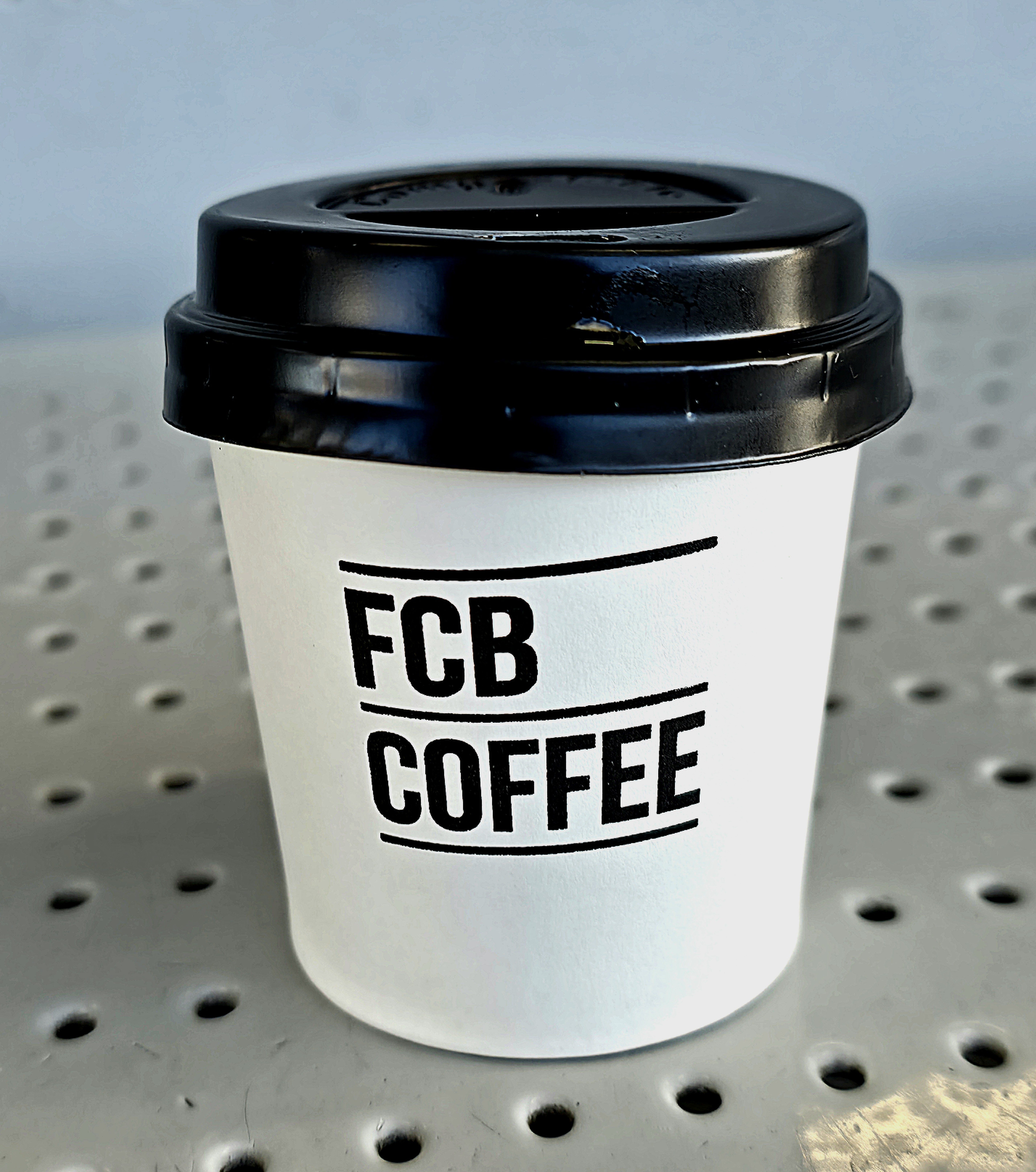 A photo showing a white Coffee cup displaying FCB, Guildford Log depicting a large intake of Coffee this year. Photo taken in Guildford Railway Station, in January 2026 by Baldi, A.K.A Amonn AL-Mahrouq
