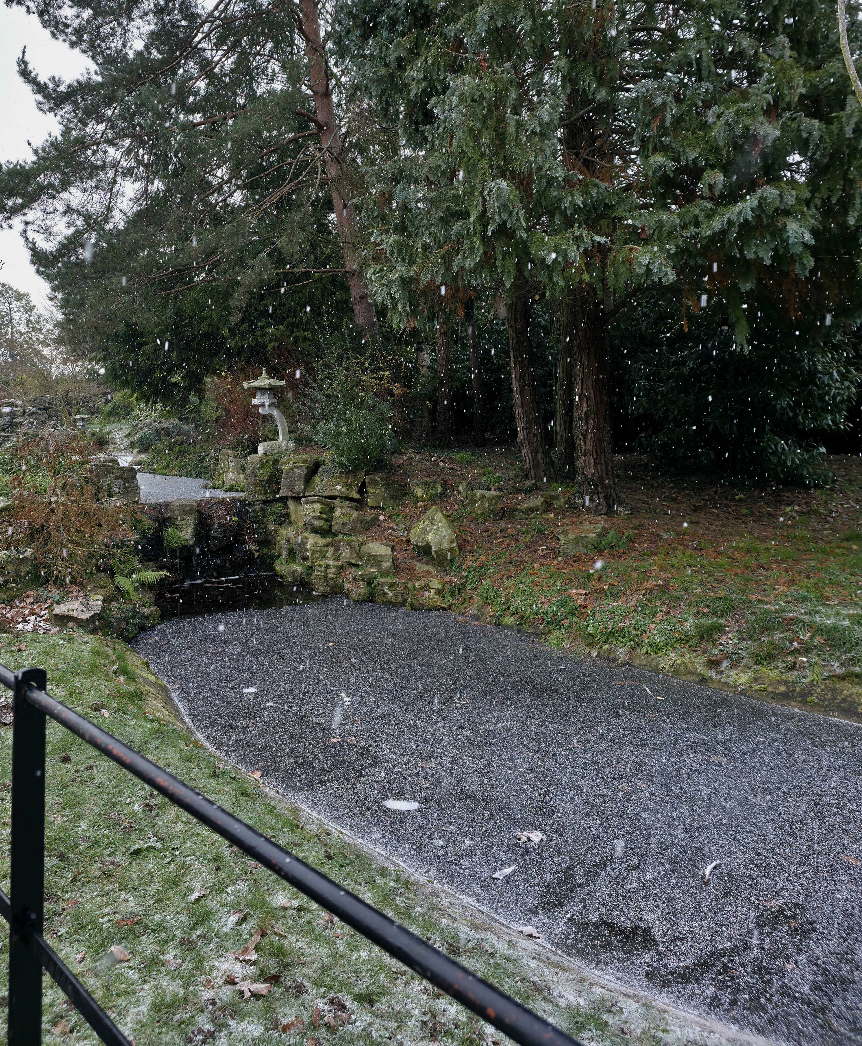 A photo taken by Baldi, A.K.A Amonn AL-Mahrouq of snow falling on a frozen stream in Stoke Park Gardens, Guildfod, Surrey, United Kingdom in January 2026.